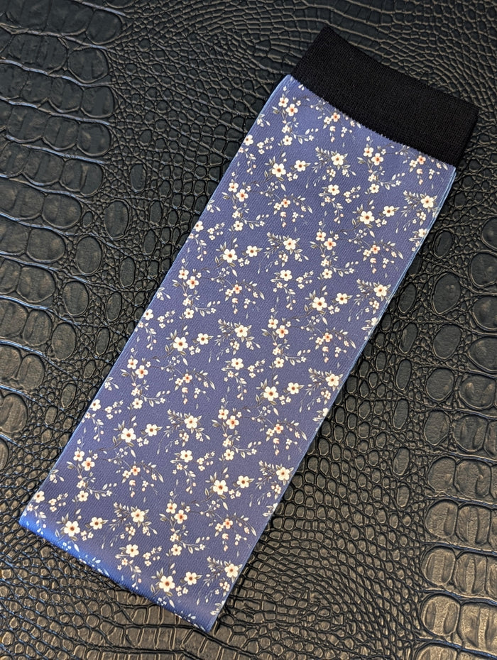 Navy sock with scattered floral pattern and black cuff displayed on a textured black surface