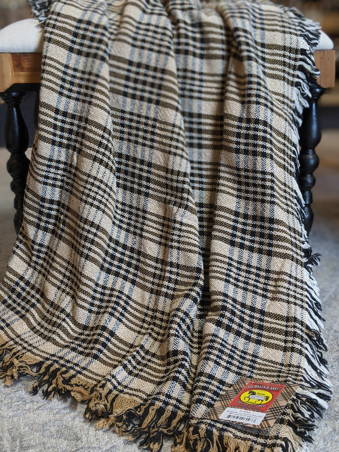 Tan, cream, and navy woven cotton plaid afghan draped over a wooden spindle chair with fringe edges.