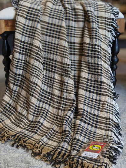 Tan, cream, and navy woven cotton plaid afghan draped over a wooden spindle chair with fringe edges.