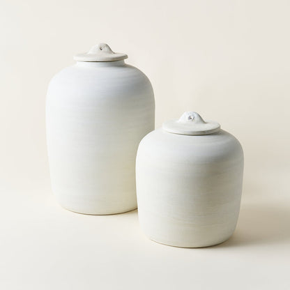 Set of two white ceramic canisters with lids in different sizes.