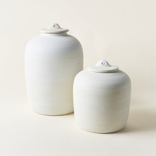 Set of two white ceramic canisters with lids in different sizes.