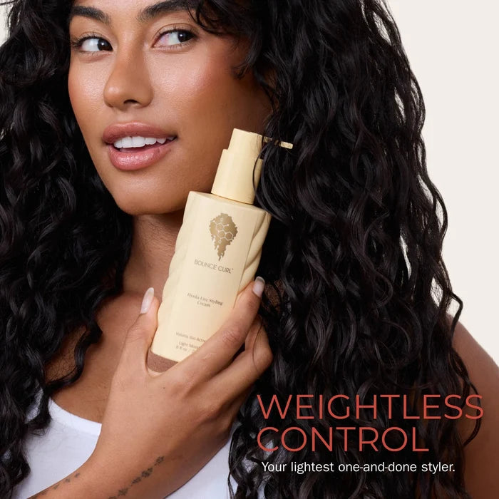 Woman holding a bottle of hydra-lite styling cream with 'Weightless Control' text on a plain background