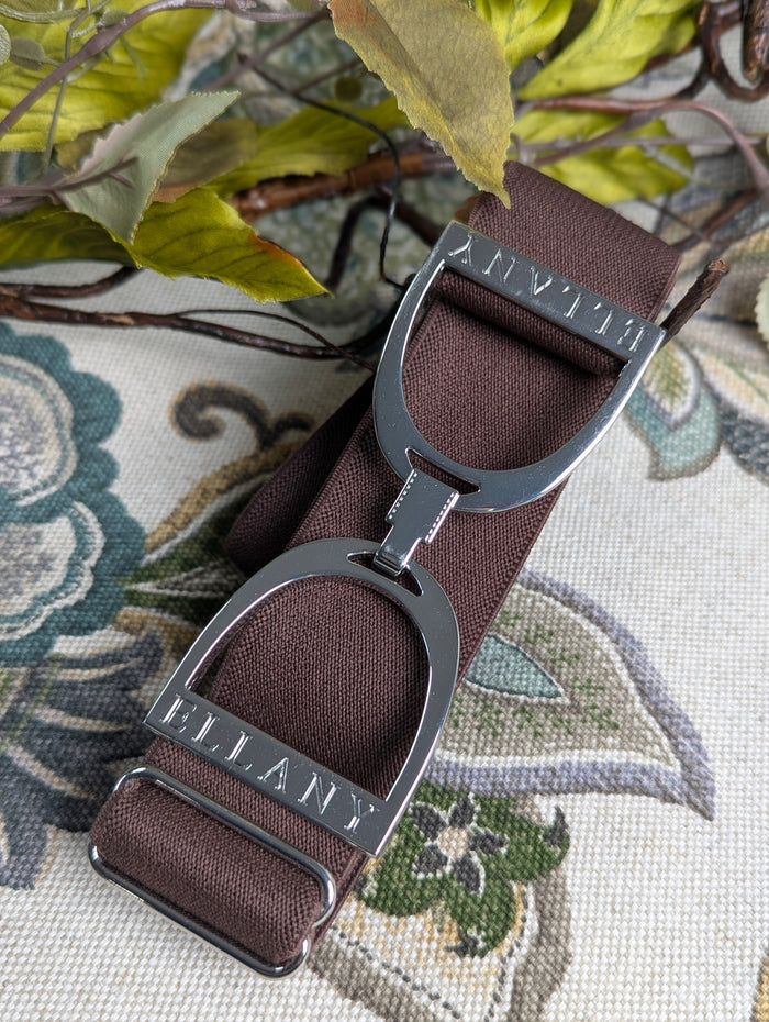 chocolate brown elastic ellany belt with silver stirrup buckle on a floral background