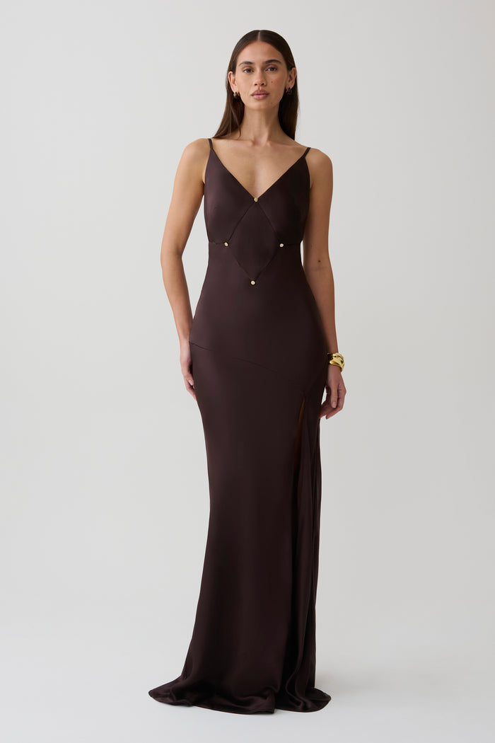 Woman wearing a dark brown v neck satin maxi dress.