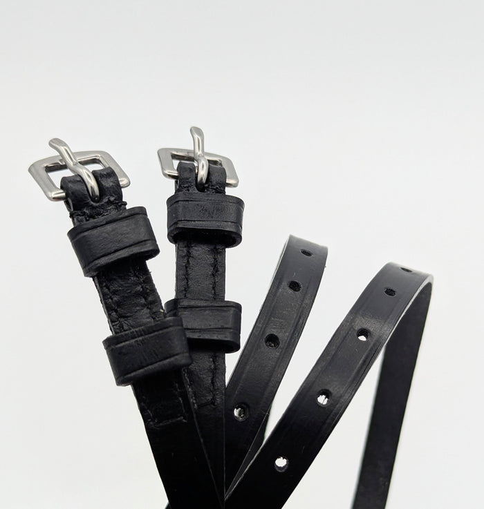 Multiple black leather spur straps arranged on a white background, highlighting smooth leather, stitched edges, adjustment holes, and square metal buckles.