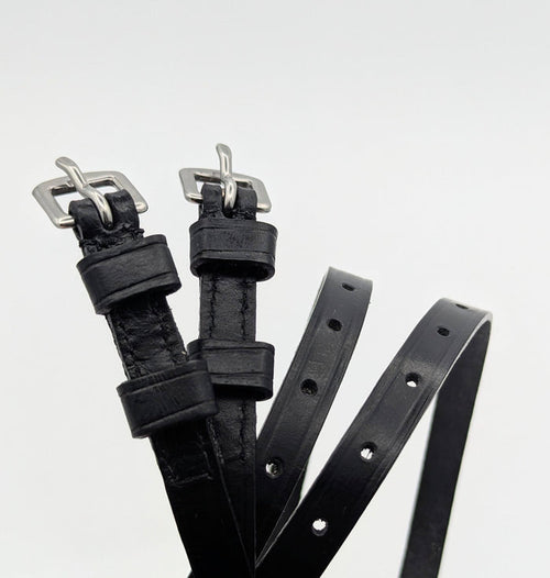 Multiple black leather spur straps arranged on a white background, highlighting smooth leather, stitched edges, adjustment holes, and square metal buckles.
