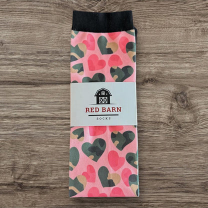 Pink tall socks with multicolor heart pattern and Red Barn Socks label, folded on a wooden surface