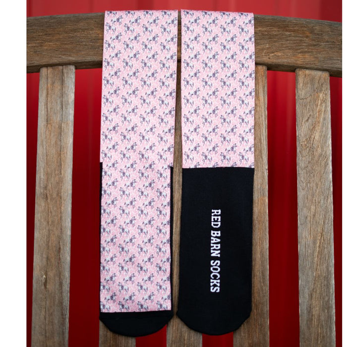 Red Barn Socks in the Giddyup Buttercup design featuring pink horse pattern displayed on a wooden surface