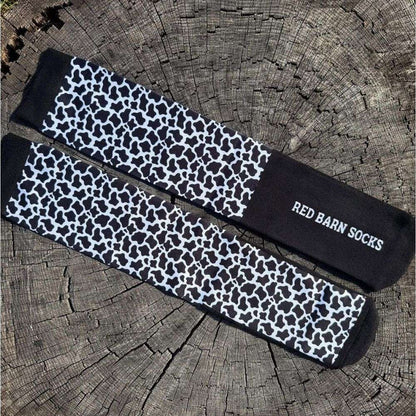 black and white cow print red barn socks on a tree stump petite height
