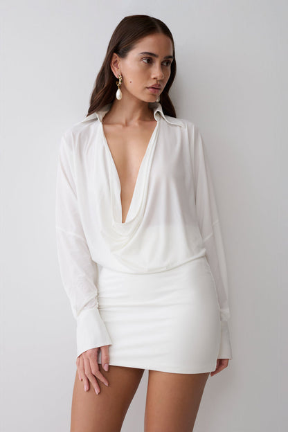 Woman wearing a white cowl drape shirt dress.